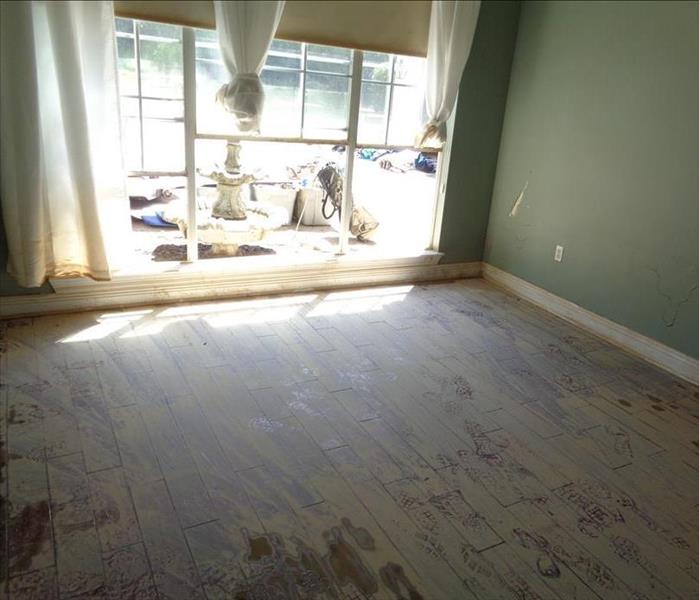 clay and dirt on wood flooring in empty room with big window