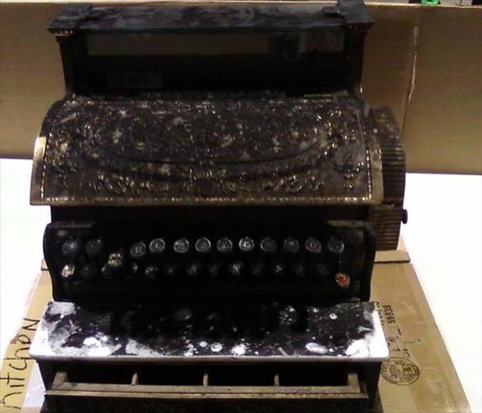 old, gold cash register covered in black soot
