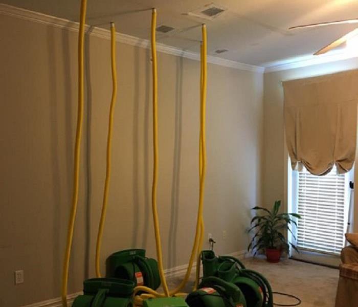 room with yellow hoses hanging from ceiling connected to green fans on the ground