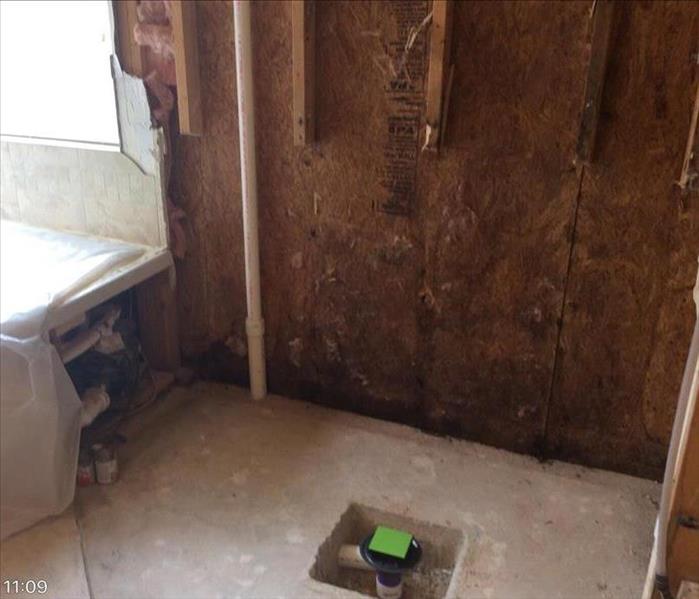 corner of bathroom with toilet removed and exposed studs half cut off 