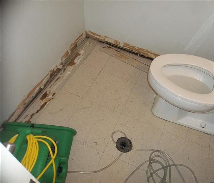 corner of bathroom with green fan on ground and baseboards removed 