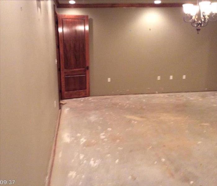 empty room with tan walls, no baseboards, concrete floor, and chandelier 