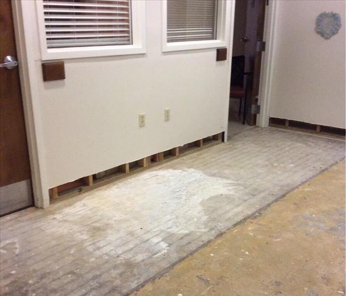 wall outside of room at senior living facility with baseboards removed and carpet and tile removed from floor 