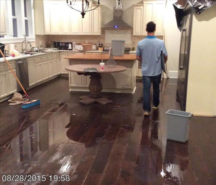 flooded kitchen with wood floors and white cabinets 