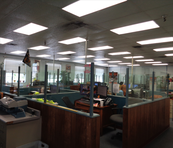 office with cubicles with glass dividers showing fire damage on ceiling tiles 