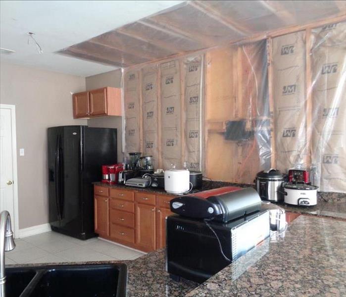 kitchen with top cabinets removed and plastic covering the exposed walls 