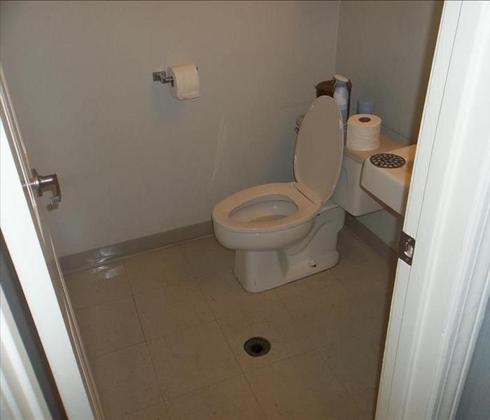 white walled bathroom with water on ground 
