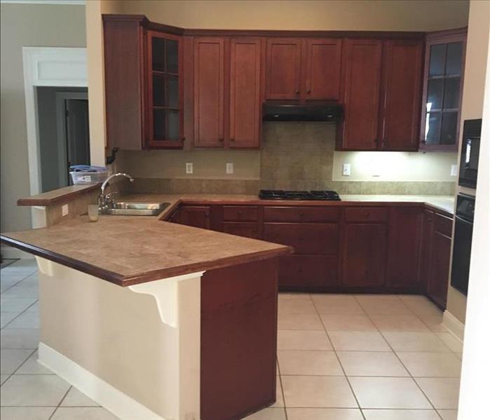 cleaned and empty kitchen with bar, stone countertops, brown wooden cabinets, and tile floors