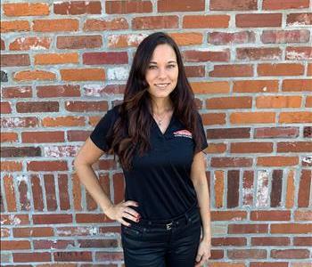 Female SERVPRO marketing manager standing in front of brick wall 