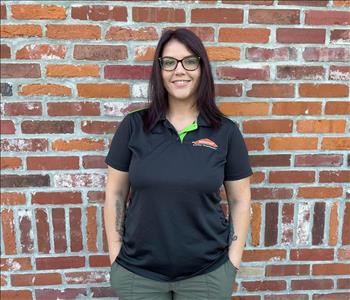 woman with black SERVPRO shirt standing in front of brick wall
