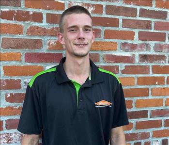 man in servpro shirt standing in front of brick wall