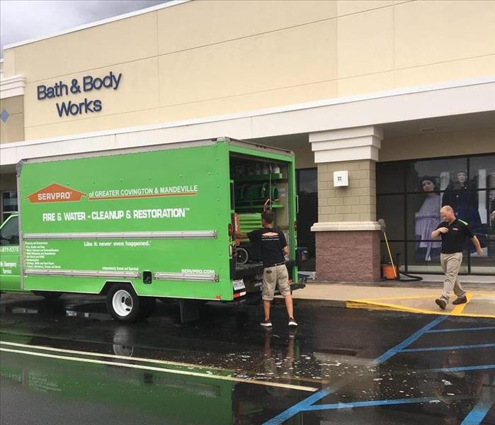 green SERVPRO box truck parked in front of Bath & Body Works store with technician getting materials from back of truck