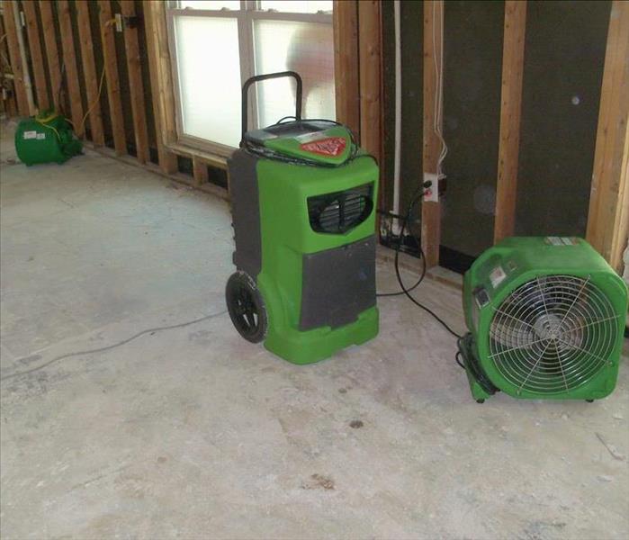 wall with sheetrock and insulation removed, exposing studs, and green fans