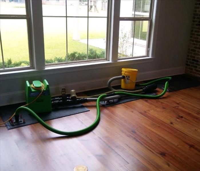 mats and hoses on top of wood flooring with window facing green backyard