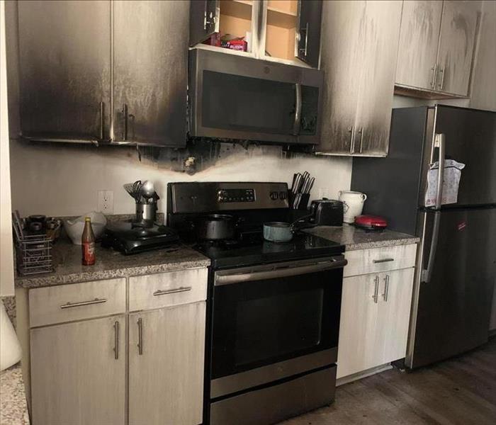 small, gray scale apartment kitchen that is damaged by fire and soot