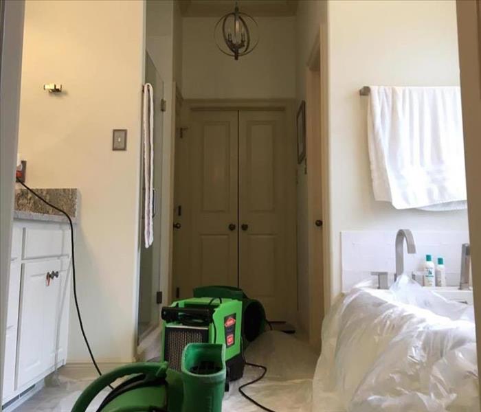 fan facing up toward bathroom ceiling with plastic over tub