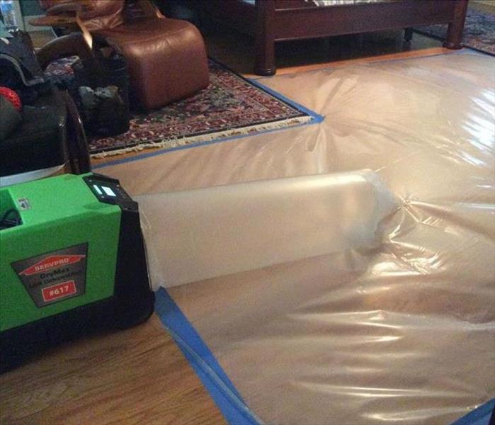 green fan with plastic taped around it and taped to wood floors 