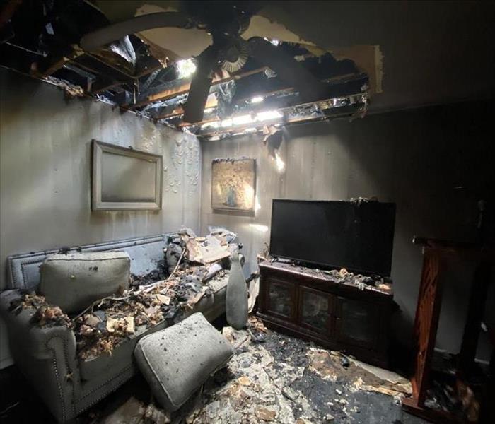 Living room with fallen ceiling and soot covered couch 