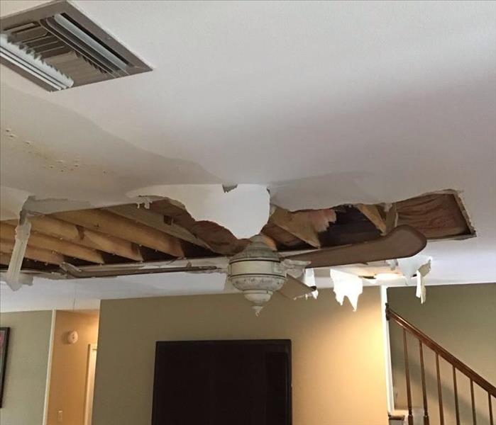 living room with ceiling partially collapsed and water damage stains on ceiling 