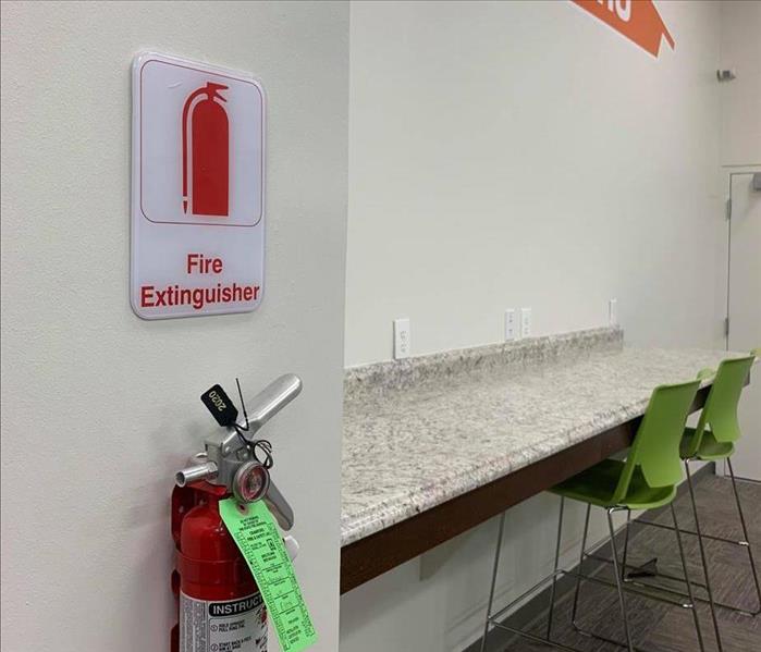 fire extinguisher on wall with orange SERVPRO sign 