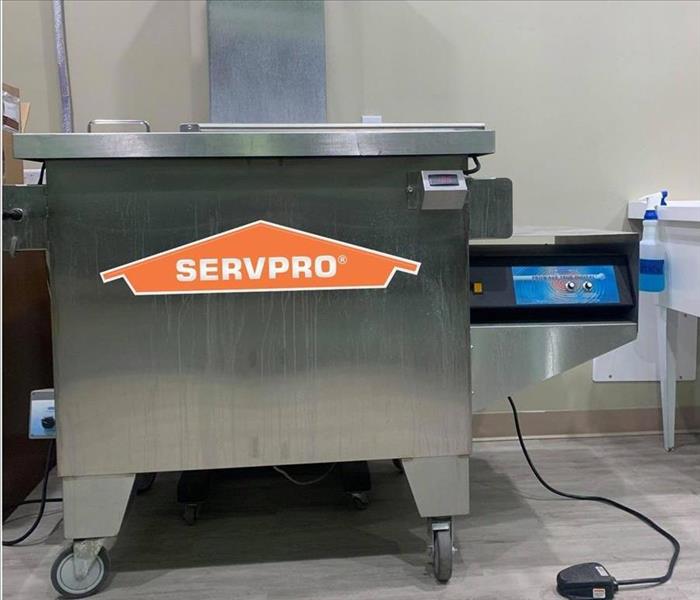 silver cleaning ultrasonic machine with orange servpro logo on it 